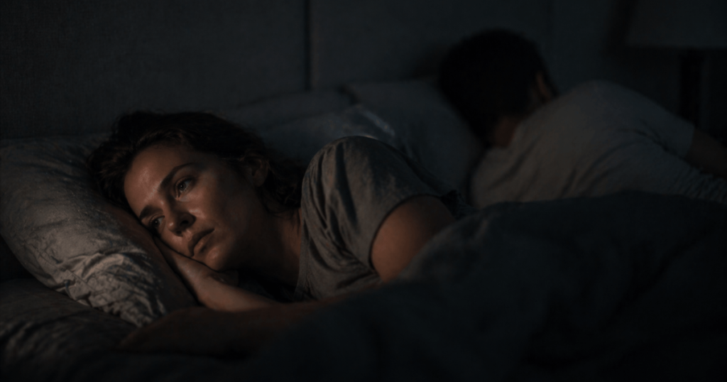 what is avoidant attachment and why does loving an avoidant hurt so much – one person lying awake looking at their partner turned away, showing emotional unavailability and one-sided connection
